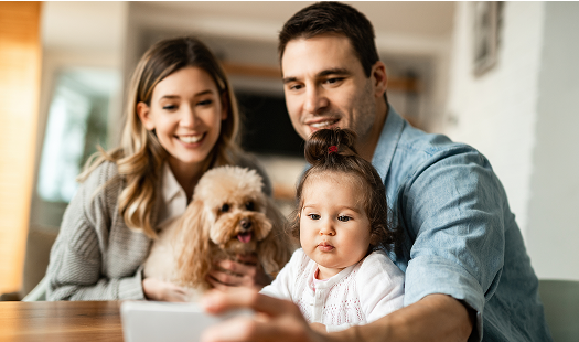 jovem familia feliz com um cachorro usando telefone inteligente enquanto toma selfie em casa o foco esta na menina